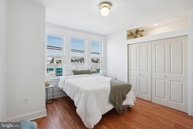 bedroom with a closet, baseboards, and wood finished floors