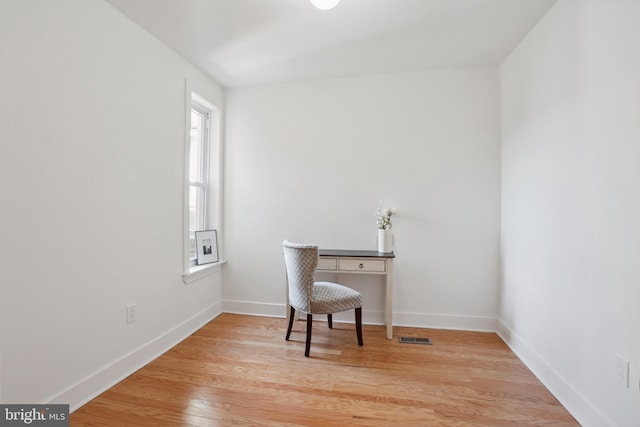 home office with light wood finished floors, visible vents, and baseboards