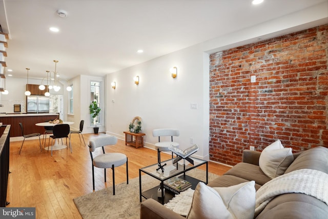 living room with recessed lighting, baseboards, light wood-style flooring, and brick wall