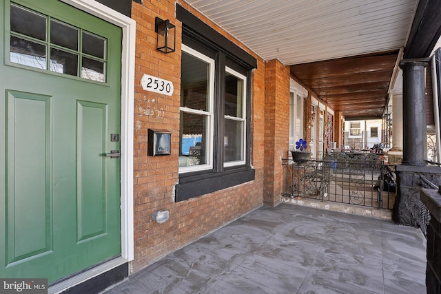 property entrance featuring a porch and brick siding