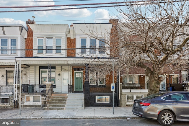 view of property with a porch and brick siding