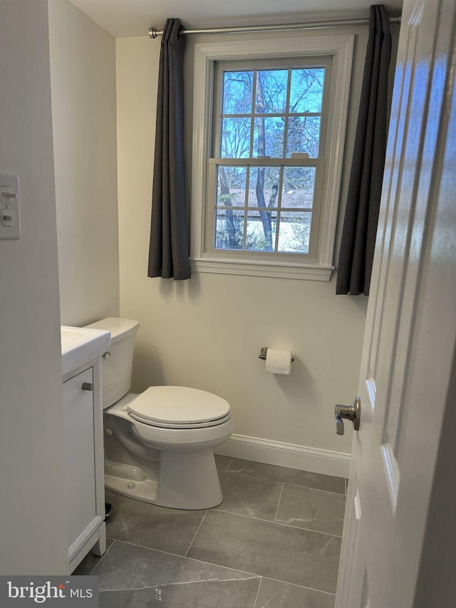 bathroom with baseboards, vanity, and toilet