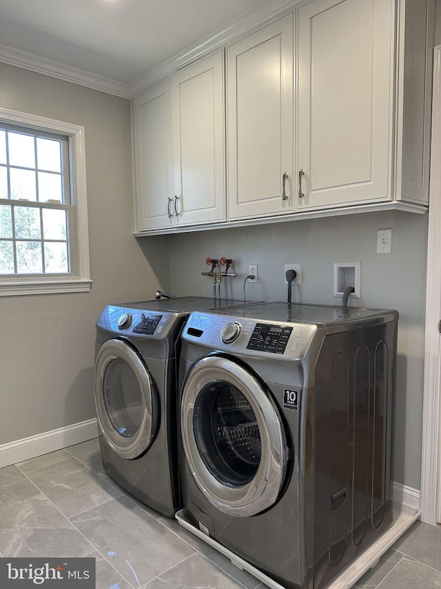 clothes washing area featuring ornamental molding, washing machine and dryer, cabinet space, and baseboards