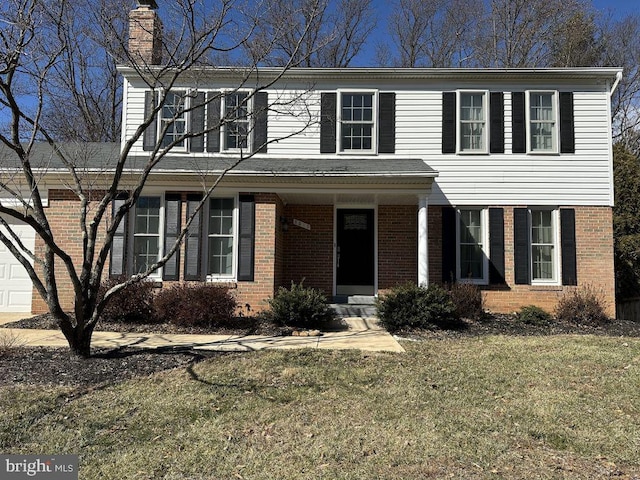 view of front of property featuring brick siding, a chimney, and a front yard