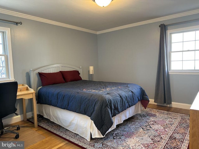 bedroom with crown molding, baseboards, and wood finished floors