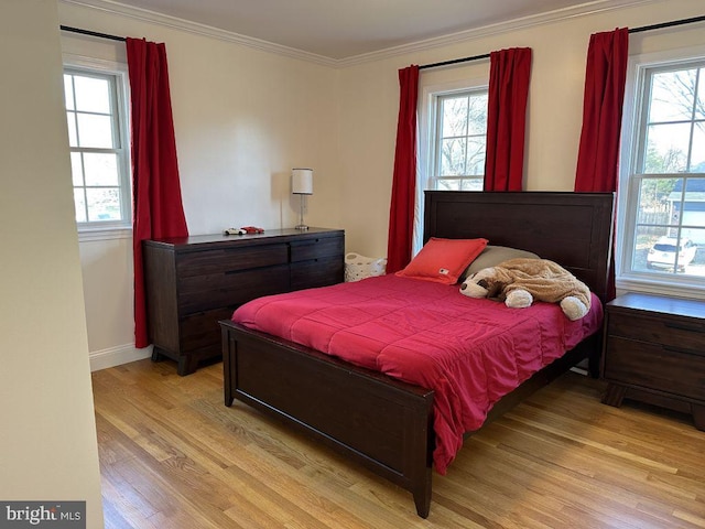 bedroom with multiple windows, crown molding, and light wood finished floors