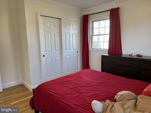 bedroom featuring light wood-type flooring, a closet, crown molding, and baseboards