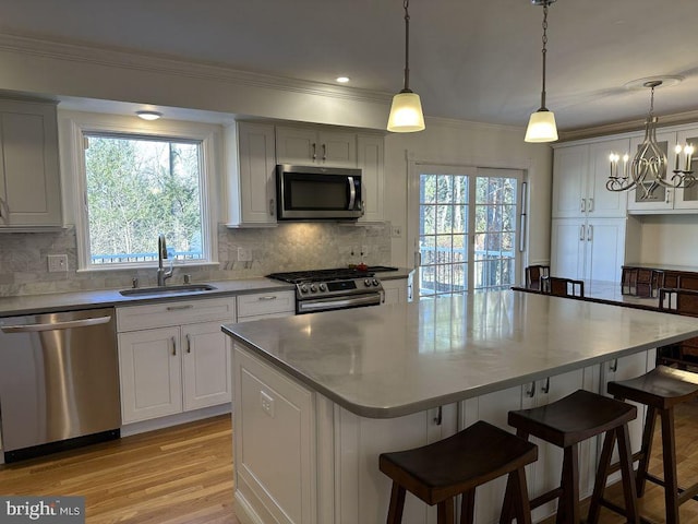 kitchen with a kitchen bar, appliances with stainless steel finishes, a sink, and a center island