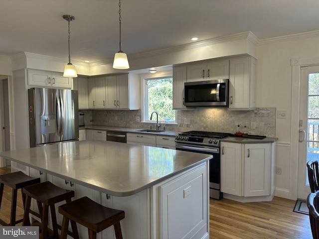 kitchen with a center island, stainless steel appliances, hanging light fixtures, decorative backsplash, and a sink