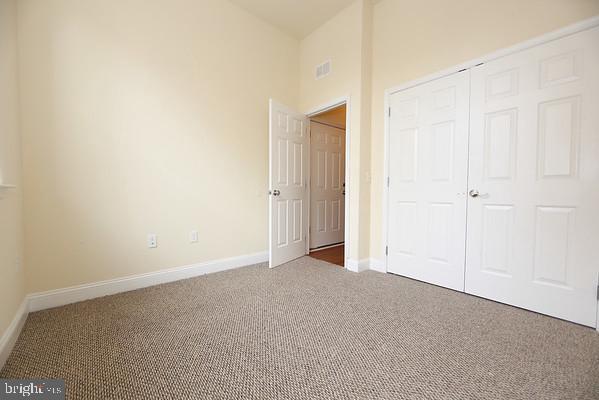 unfurnished bedroom featuring a closet, carpet flooring, visible vents, and baseboards