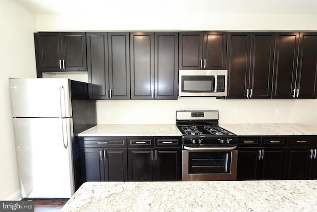 kitchen featuring appliances with stainless steel finishes and light stone counters