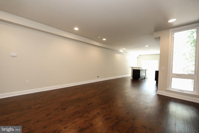 unfurnished living room with baseboards, dark wood finished floors, and recessed lighting