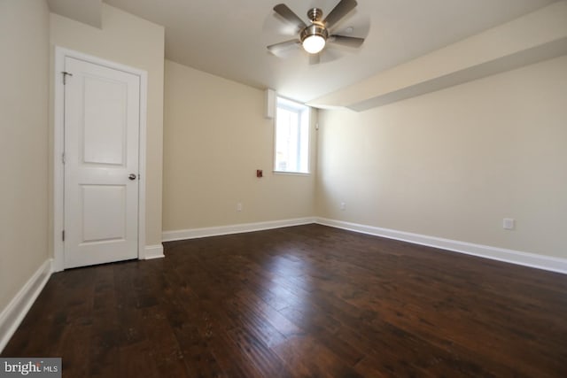 unfurnished room featuring dark wood-style floors, a ceiling fan, and baseboards