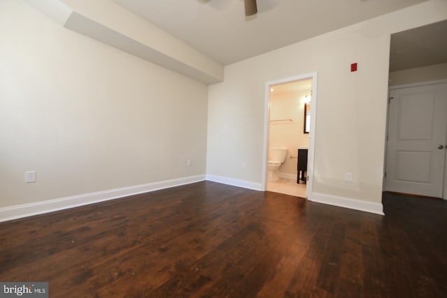 unfurnished bedroom featuring dark wood-style flooring, baseboards, and ensuite bathroom