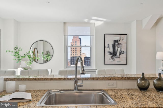 kitchen featuring a sink and light stone counters