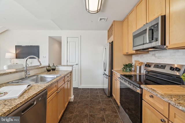 kitchen with light brown cabinets, appliances with stainless steel finishes, tasteful backsplash, and a sink