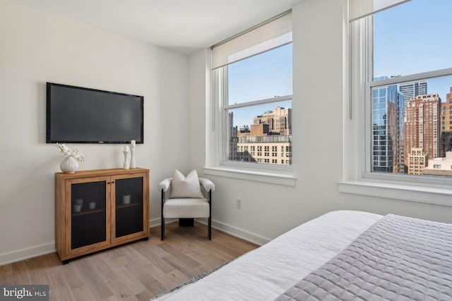 bedroom with a city view, baseboards, and wood finished floors