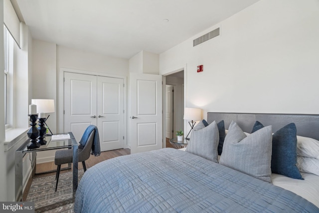 bedroom with a closet, visible vents, and wood finished floors