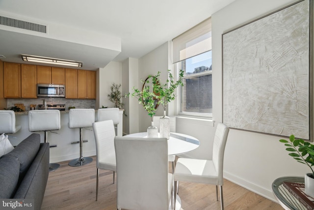 dining space with light wood-style flooring, baseboards, and visible vents