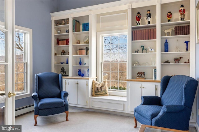 sitting room featuring plenty of natural light, baseboard heating, and light carpet