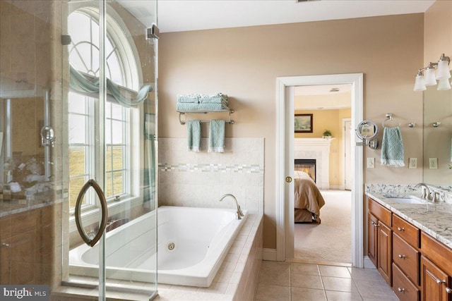 ensuite bathroom featuring a whirlpool tub, ensuite bath, a fireplace, tile patterned flooring, and vanity