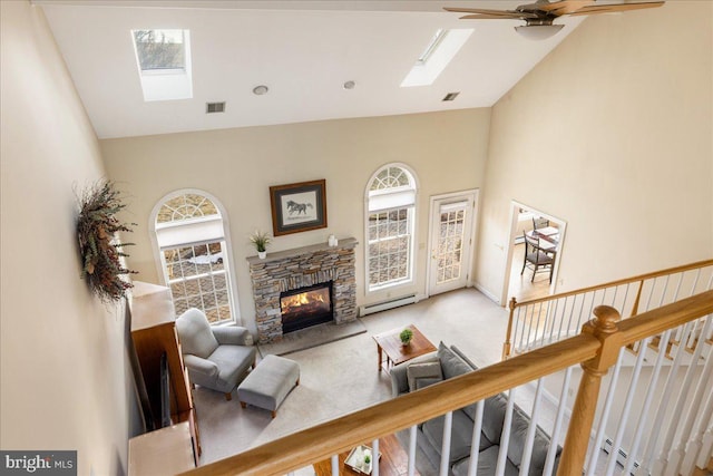 living room featuring visible vents, a baseboard radiator, a skylight, a fireplace, and carpet flooring