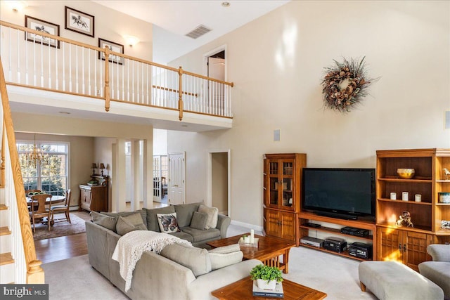 living room featuring visible vents, baseboards, wood finished floors, an inviting chandelier, and a towering ceiling