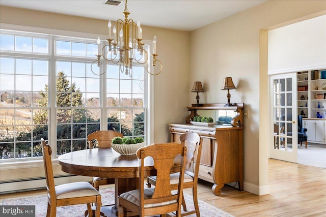 dining space with visible vents, baseboards, a baseboard radiator, light wood-type flooring, and a chandelier