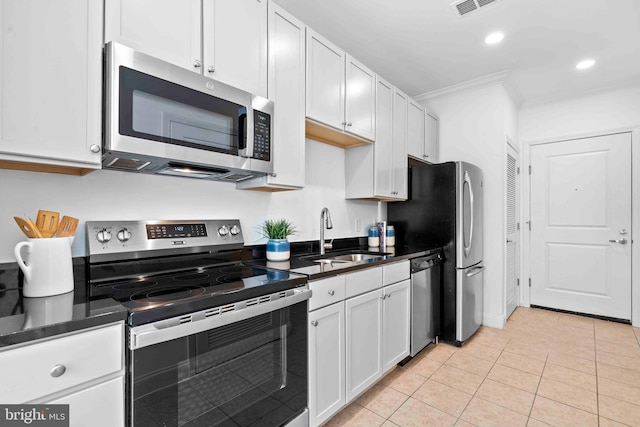 kitchen featuring stainless steel appliances, dark countertops, white cabinets, and a sink