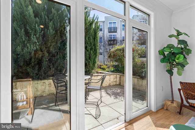 doorway to outside with ornamental molding, wood finished floors, and baseboards