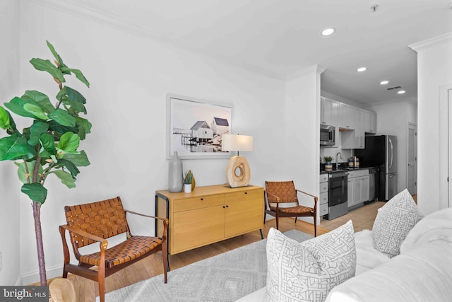 living area with light wood-style flooring, crown molding, and recessed lighting