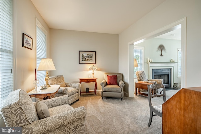 living room with a fireplace with flush hearth, light carpet, plenty of natural light, and baseboards