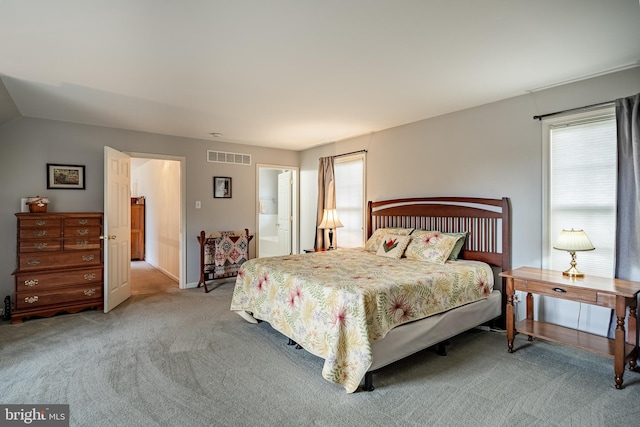 bedroom with ensuite bath, visible vents, and light colored carpet