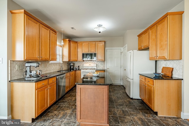 kitchen featuring visible vents, a kitchen island, appliances with stainless steel finishes, decorative light fixtures, and a sink