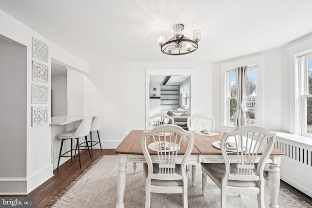 dining space with a chandelier, dark wood-style flooring, and baseboards