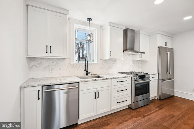 kitchen featuring stainless steel appliances, wall chimney exhaust hood, a sink, and white cabinetry