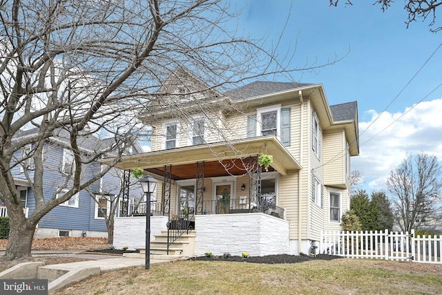 view of front of home with a shingled roof, fence, a porch, and a front lawn