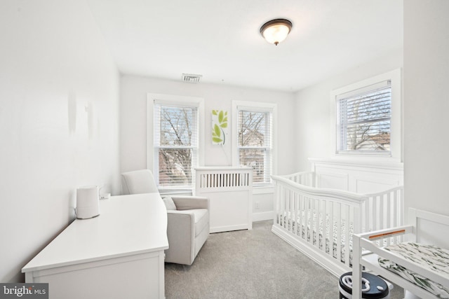 bedroom featuring a crib, multiple windows, visible vents, and light colored carpet