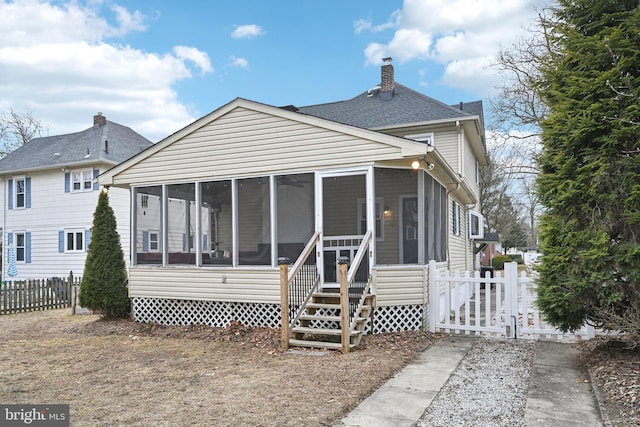 back of house featuring roof with shingles, a chimney, fence, and a sunroom