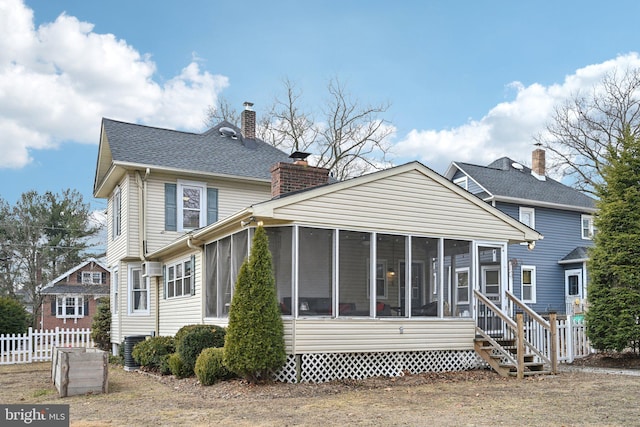 rear view of house featuring a sunroom, a chimney, fence, and roof with shingles