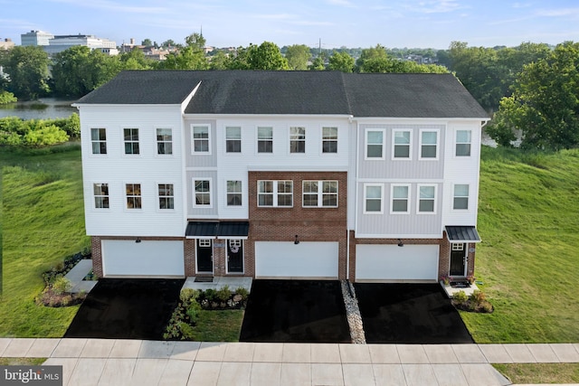 multi unit property featuring aphalt driveway, a standing seam roof, brick siding, and an attached garage