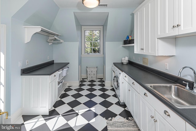 kitchen featuring dark countertops, dark floors, white cabinets, and a sink