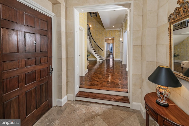 entryway with ornamental molding, baseboards, and stairs