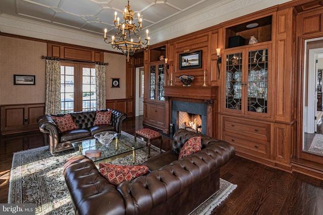 living area featuring french doors, crown molding, dark wood finished floors, a fireplace, and wainscoting