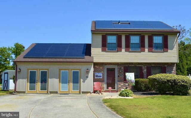 view of front of home with solar panels, french doors, a front lawn, and brick siding