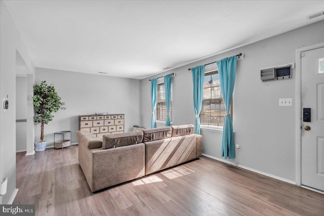 living room with baseboards, visible vents, and wood finished floors