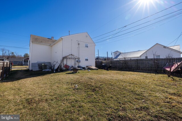 rear view of property with a yard and a fenced backyard