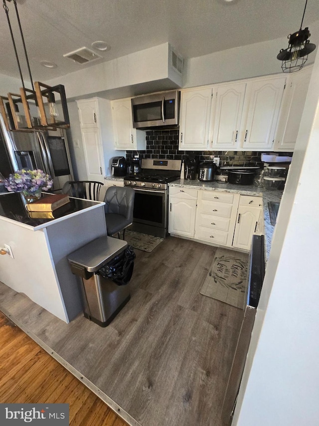 kitchen featuring white cabinets, visible vents, stainless steel appliances, and dark wood finished floors