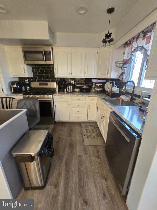 kitchen featuring decorative backsplash, dark wood-type flooring, stainless steel appliances, white cabinetry, and a sink