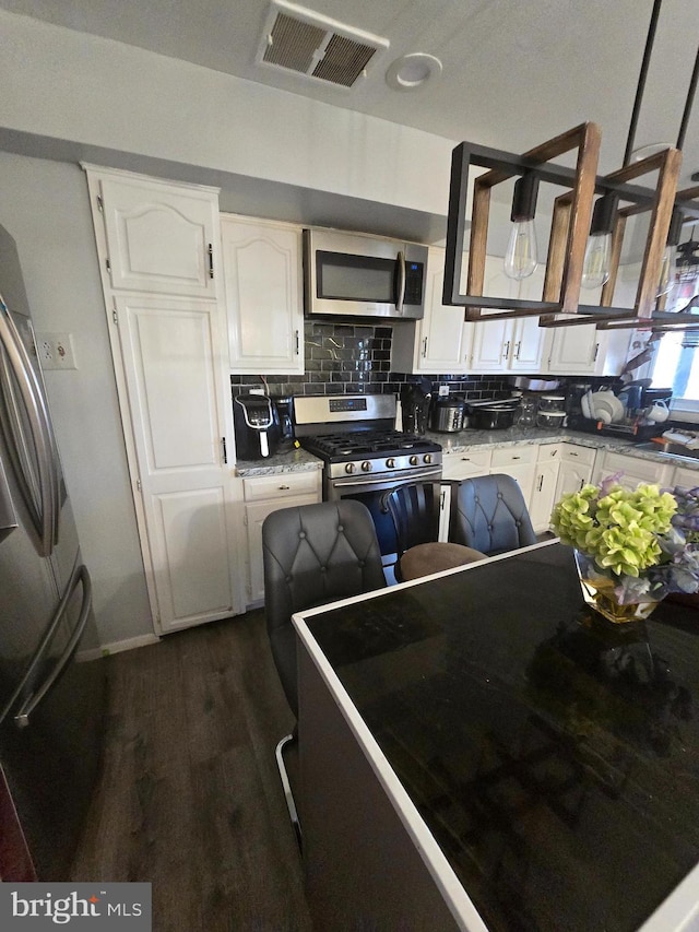 kitchen featuring visible vents, decorative backsplash, appliances with stainless steel finishes, dark wood-type flooring, and white cabinets